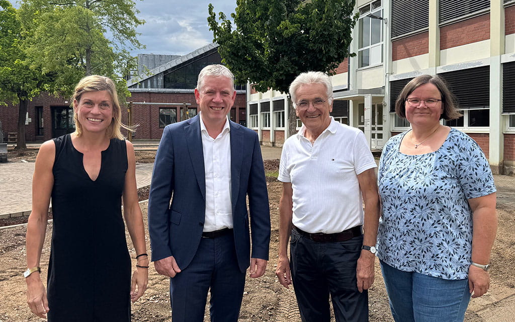 Vier Personen auf einer Baustelle vor einem Baum